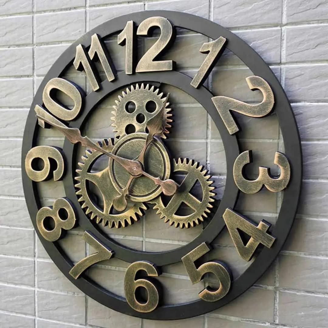 A decorative wall clock with a dark frame and bronze-colored numbers and gears.