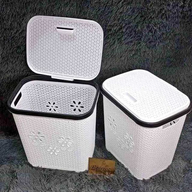 Two white plastic laundry hampers with a basket weave texture and perforated lids.