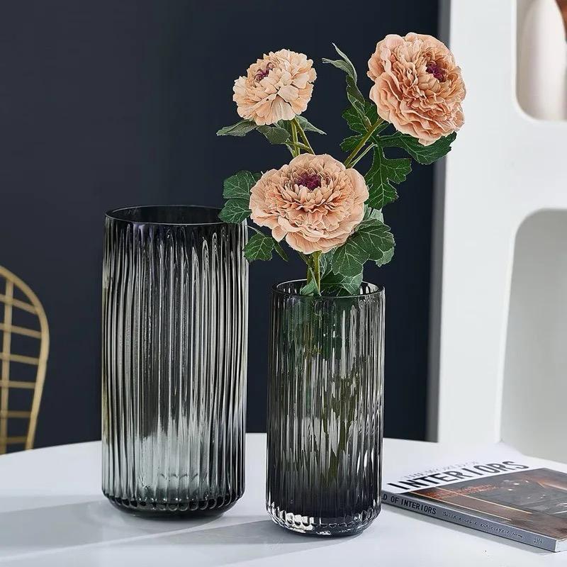 A dark gray translucent cylindrical glass vase with vertical fluted ridges.