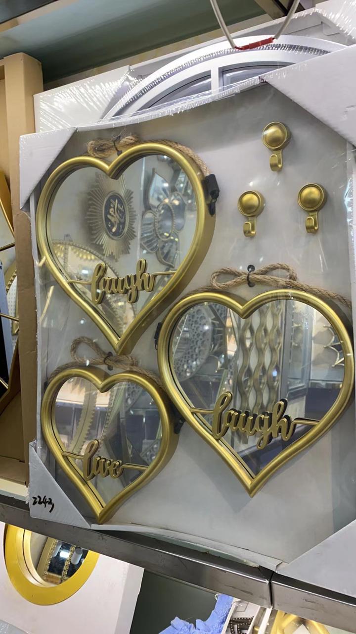 A set of three heart shaped wall mirrors in gold and black finishes arranged in descending sizes.