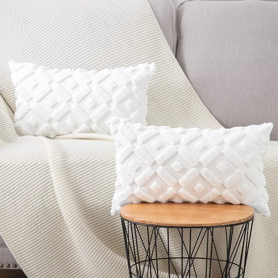 Two textured white decorative pillow covers with a raised diamond pattern