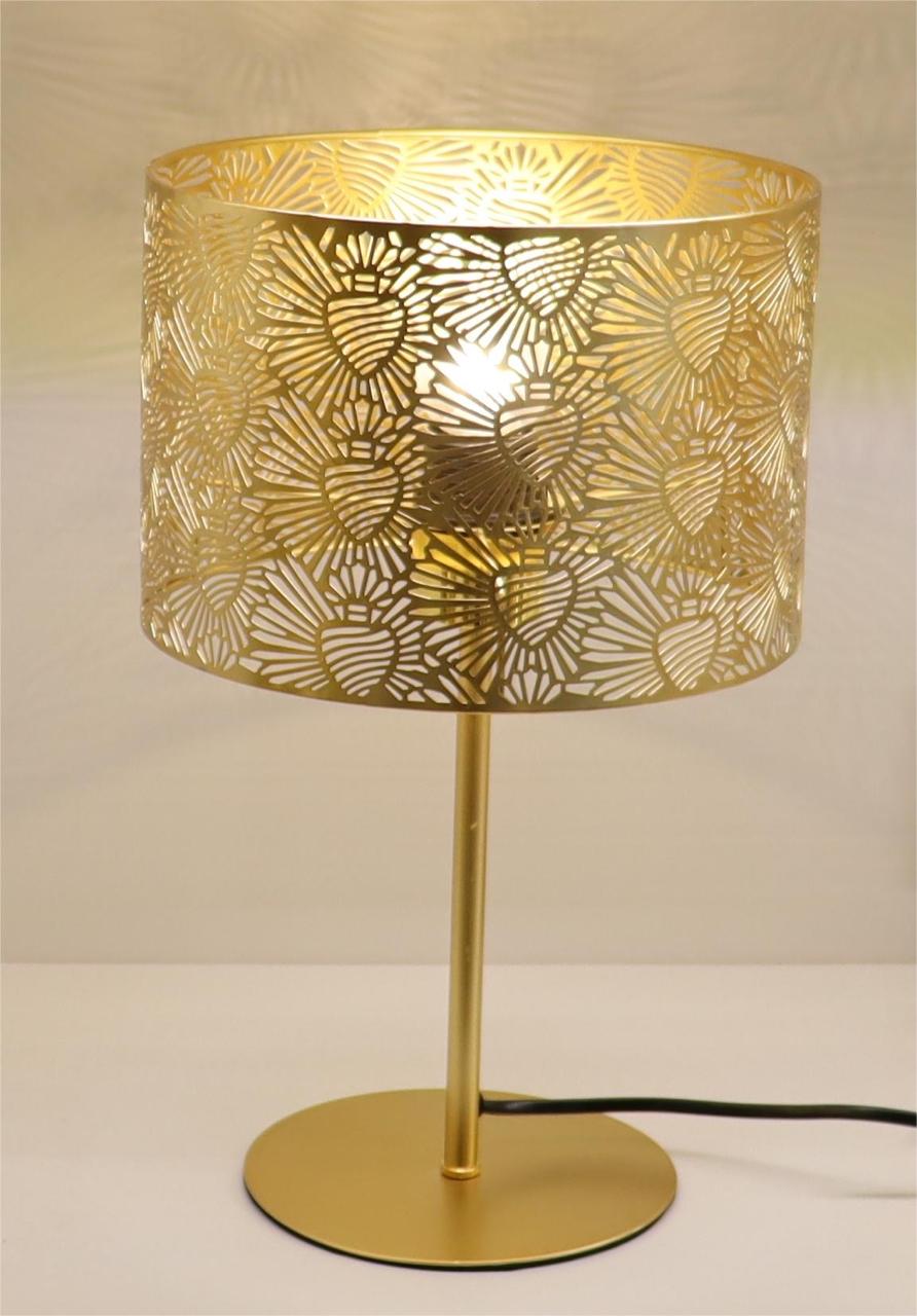 A gold table lamp with a cylindrical metal shade featuring intricate floral cutout patterns on a round flat base.