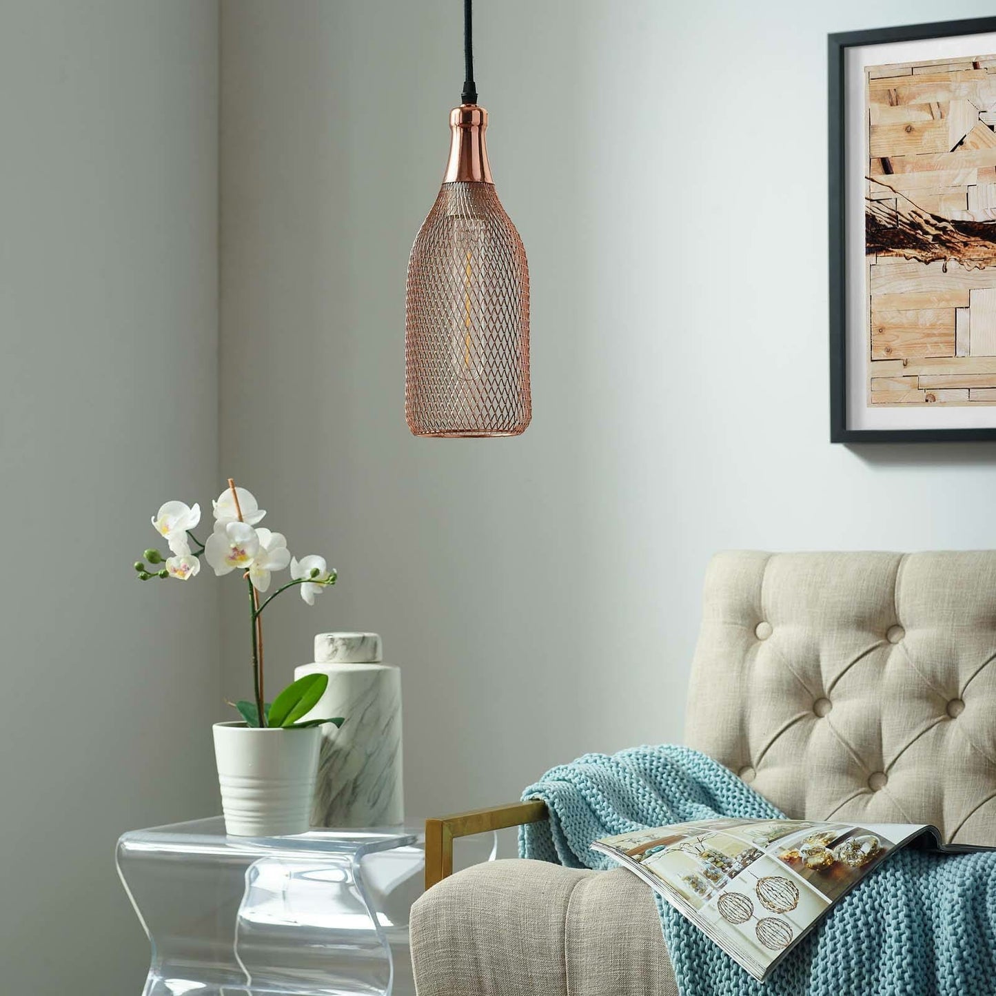 A pendant light fixture shaped like a wine bottle with a rose gold metal mesh shade