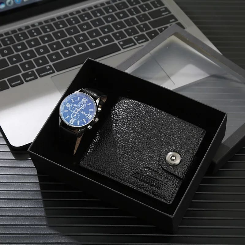 A black gift box containing a black watch with a blue dial and a matching black textured wallet with a snap closure, displayed on a laptop keyboard.