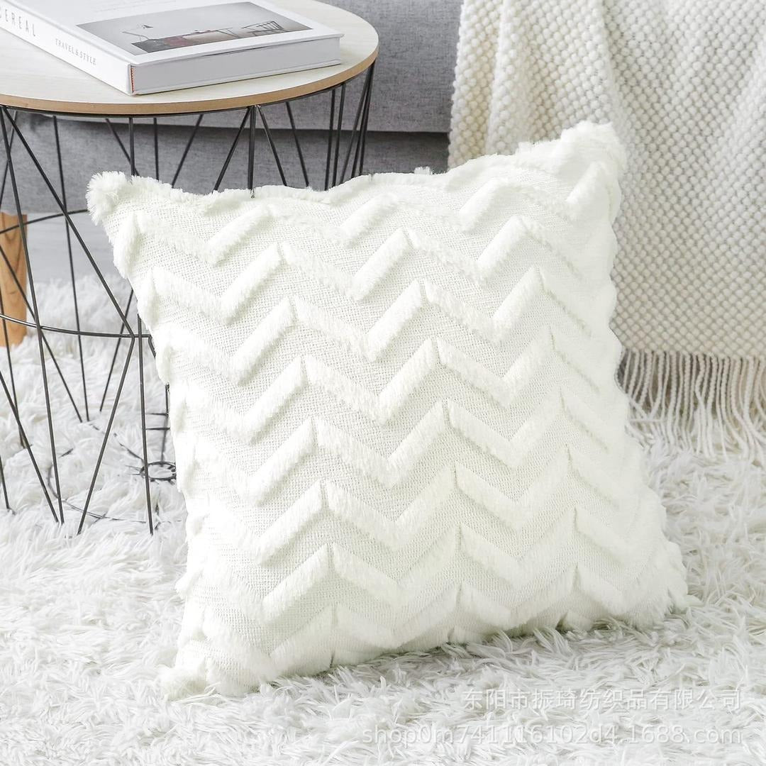 A close up of a cream plush pillow with diagonal pleats and a vertical gold stripe