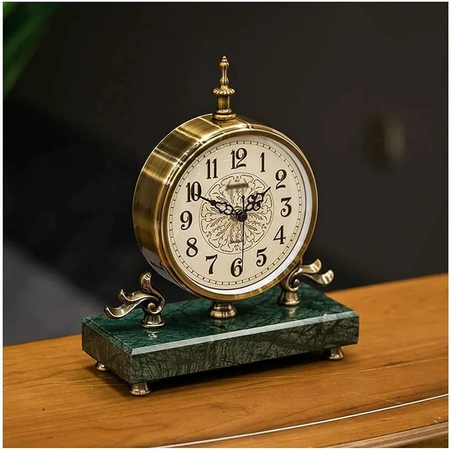 An antique brass desk clock with a classical white face on a green marble base.