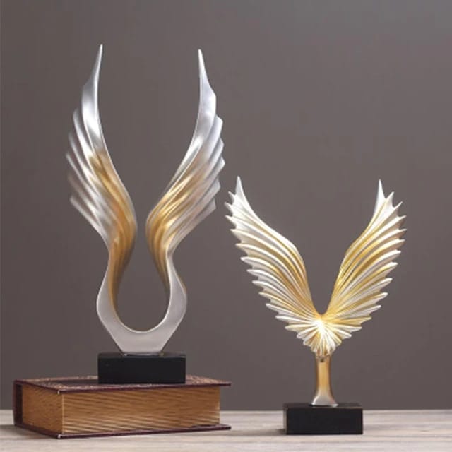 An abstract resin sculpture of silver and gold eagle wings on a black base.