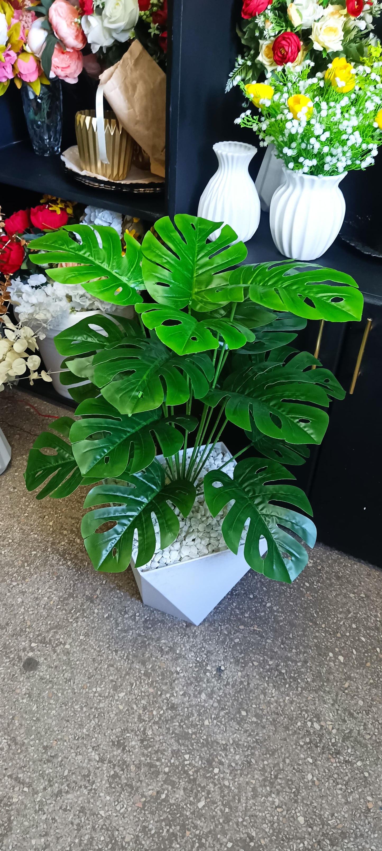 An artificial Monstera plant with wavy green leaves