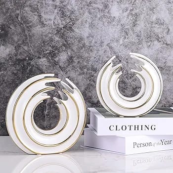 Two white circular ceramic vases with gold trim and a hollow center