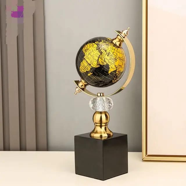 A black and gold world globe on a crystal accent and black cube base.
