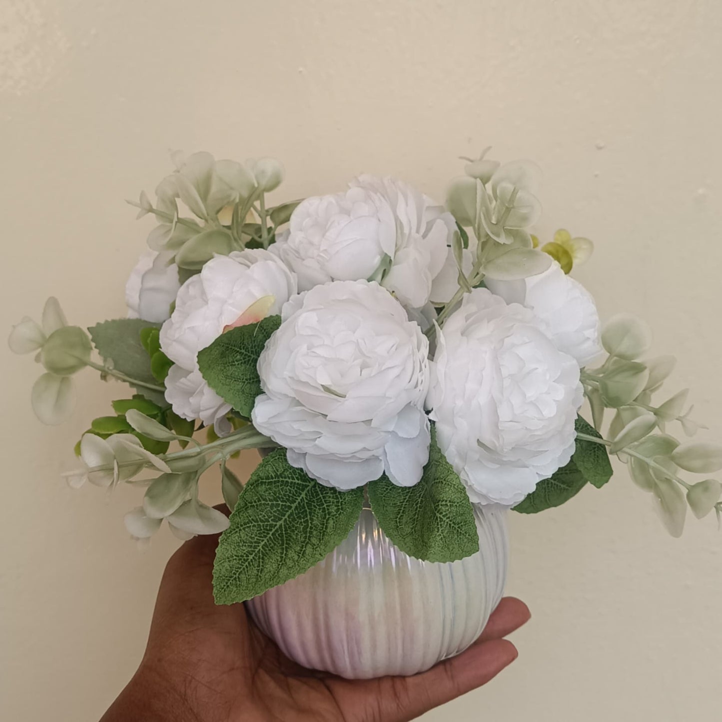 A small white ceramic vase containing colorful artificial flowers