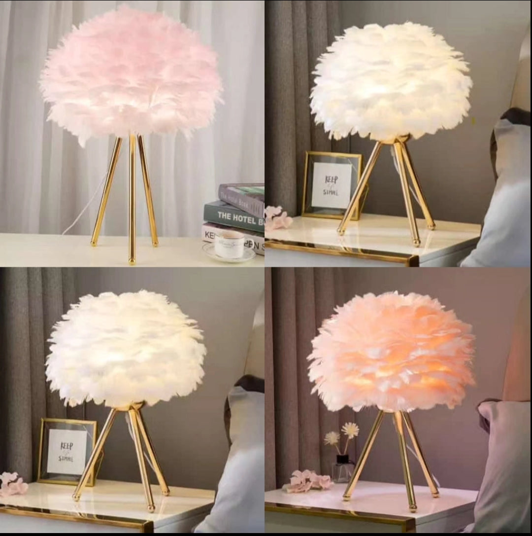 A table lamp with a fluffy pink feather shade and gold tripod legs