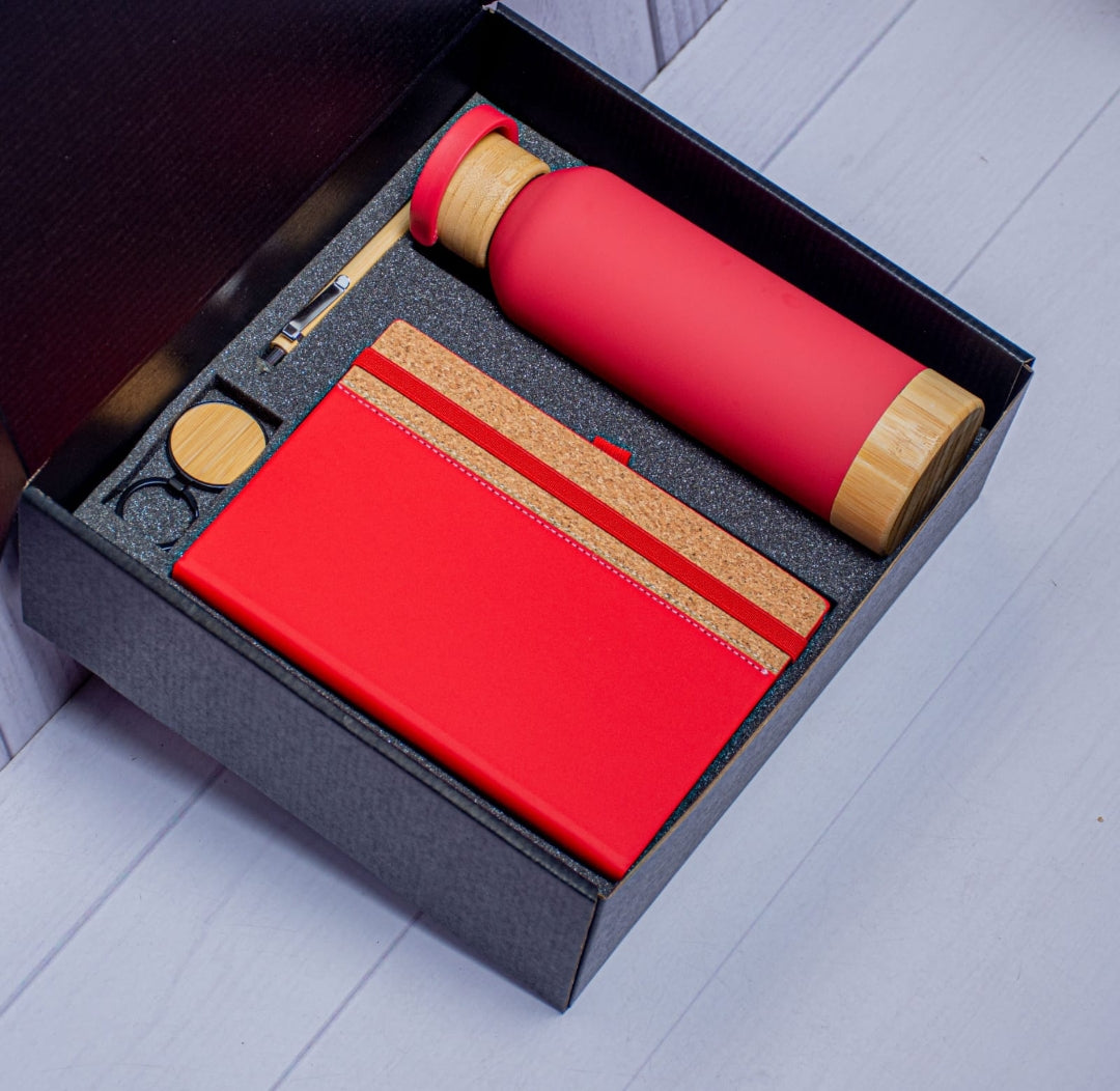 Executive gift set in a black box featuring a red thermal bottle with wood accents and a matching red notebook with a cork spine.