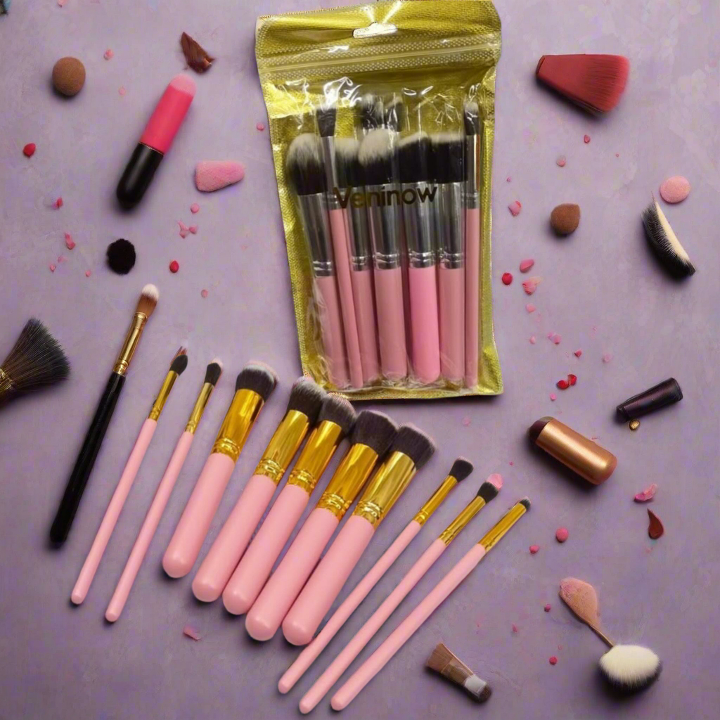 A set of ten pink-handled makeup brushes with gold accents, arranged on a purple background with various makeup tools and powder puffs scattered around.