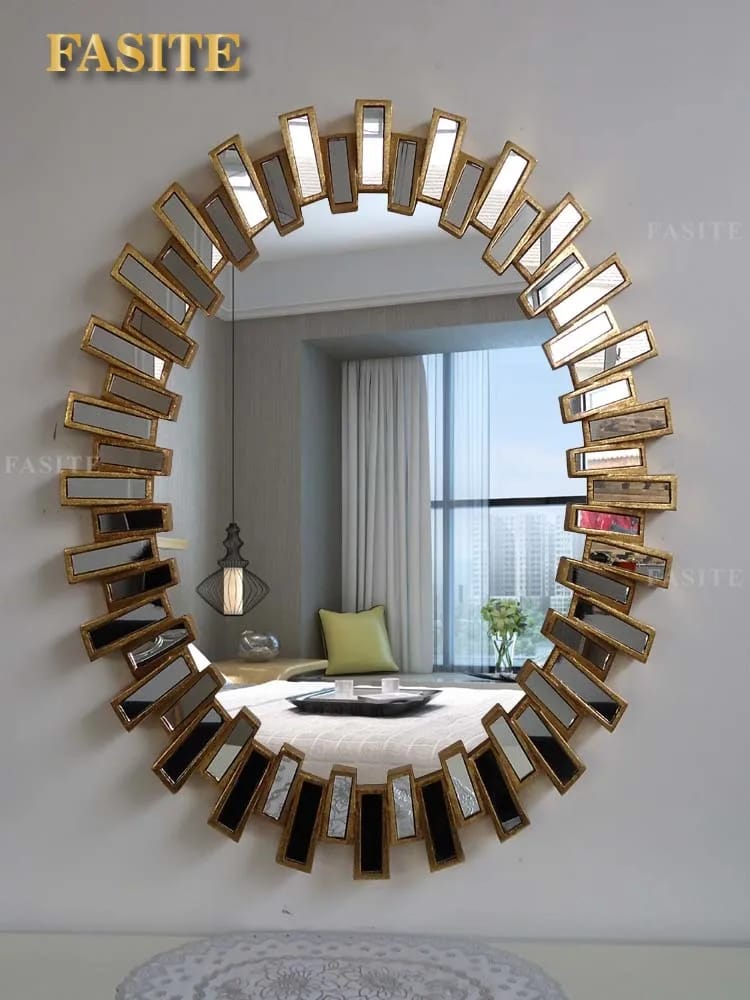 A large round decorative wall mirror with a gold sunburst geometric frame.