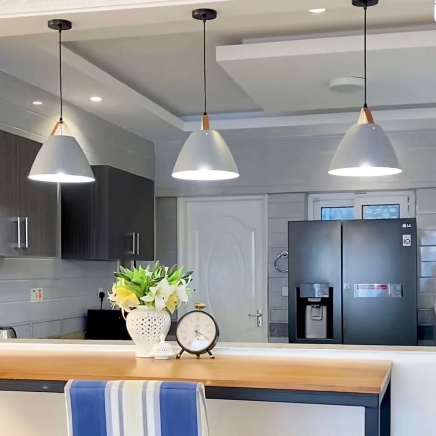 Three grey bluish cone shaped pendant lights with wood accents.
