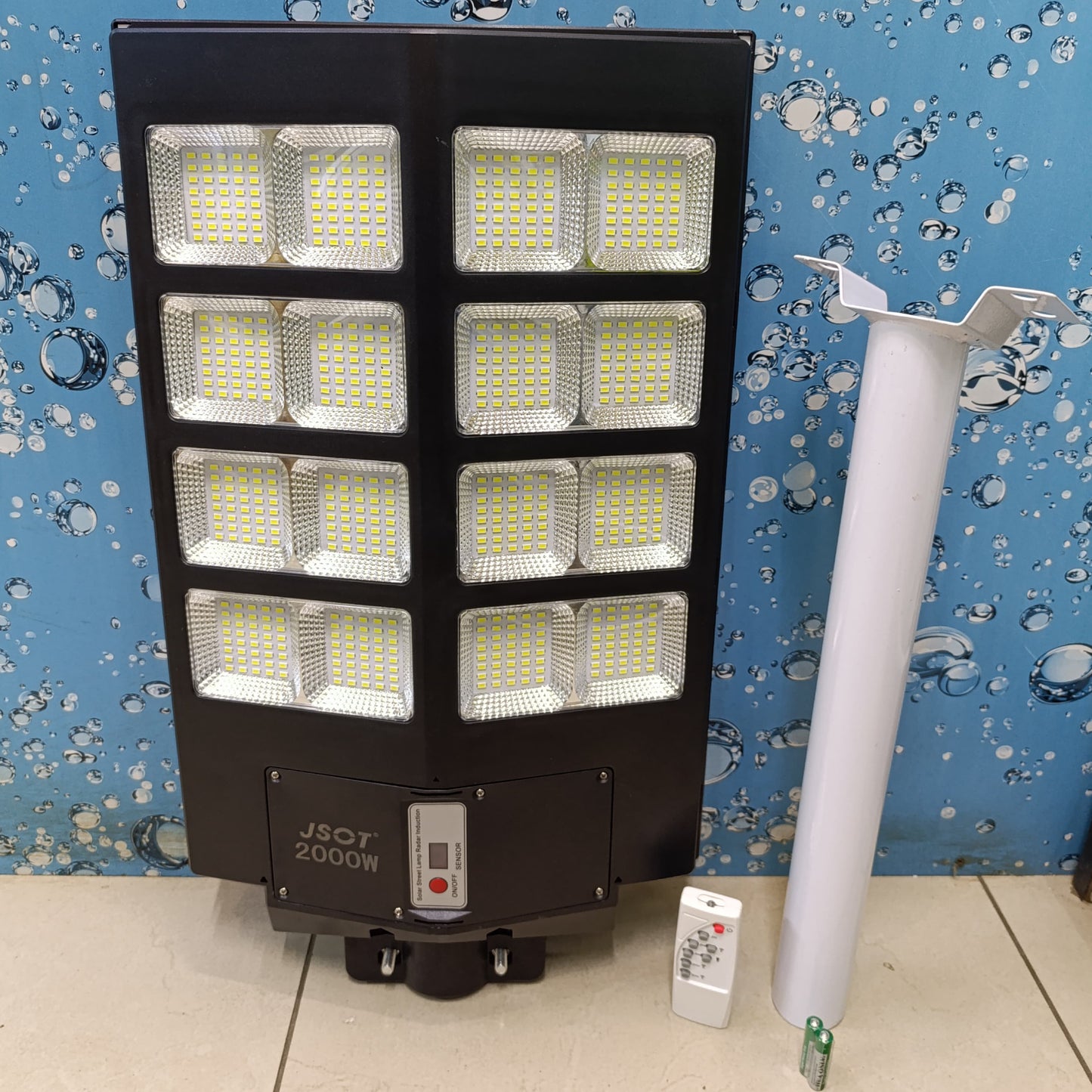 Large black solar street light with eight LED panels shown with a white mounting pole and remote control.