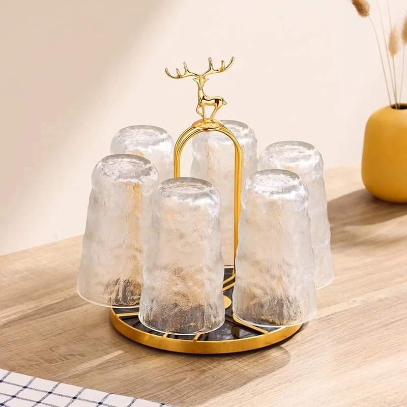 Gold tone rotating glass cup holder stand featuring a deer emblem handle