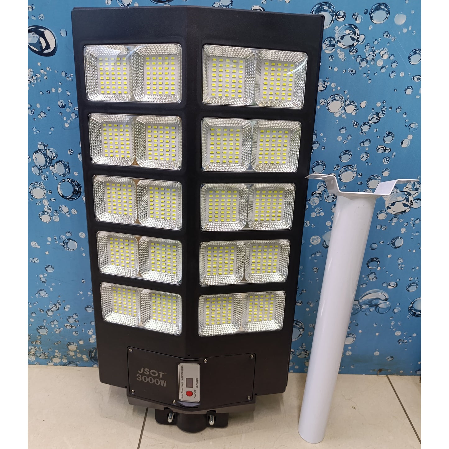 Large grey solar street light with ten LED panels, a mounting pole, and a remote control.