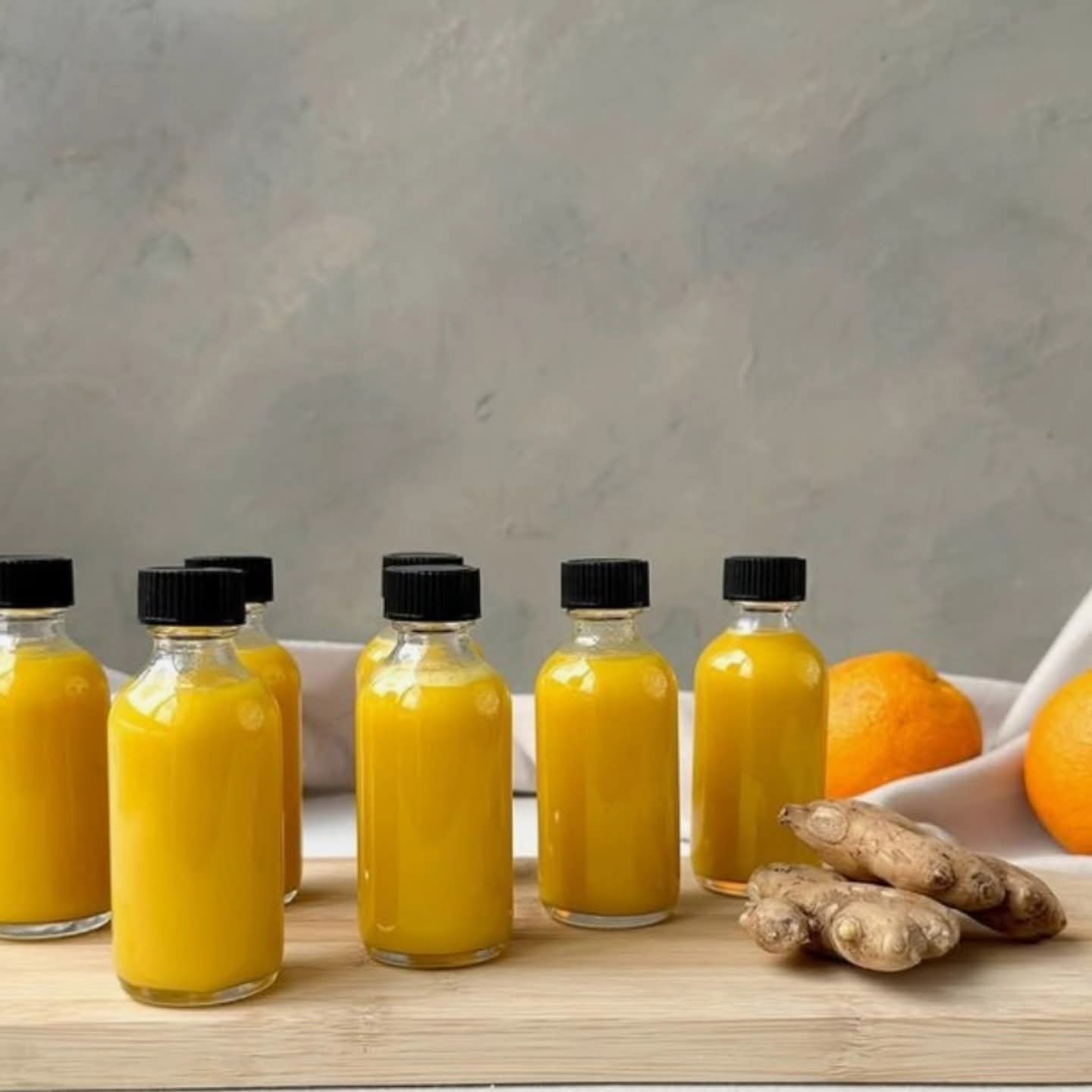 Six small, clear glass juice bottles with black screw caps,