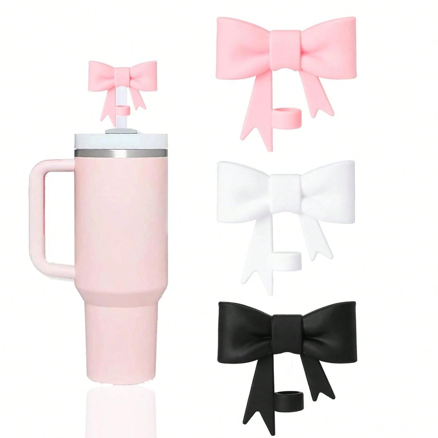 Three large bow shaped silicone straw covers in pink, white, and black, next to a pink tumbler with a small pink bow topper on its straw.