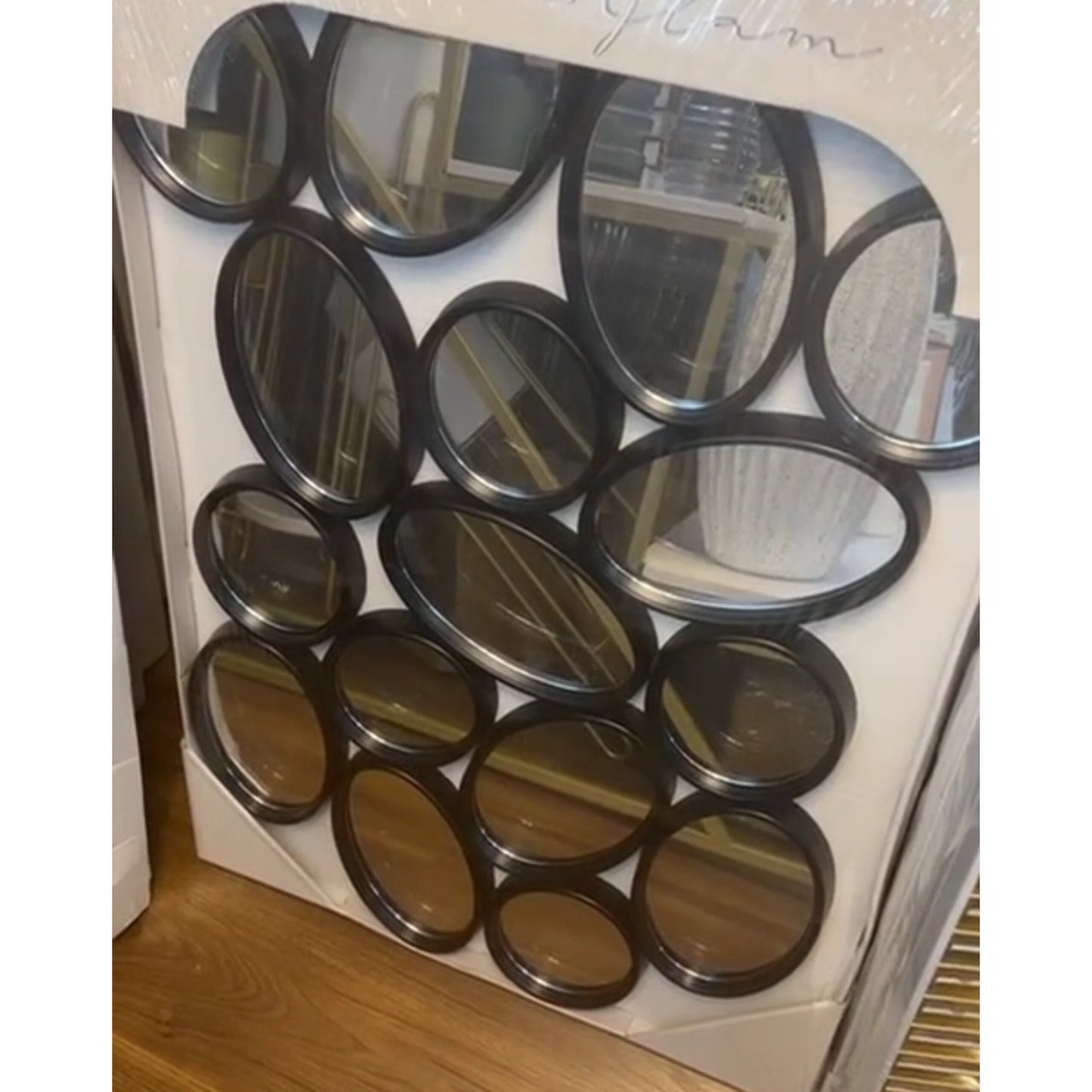 Wall décor mirror featuring sixteen interconnected black circular and oval frames in an artistic cluster.