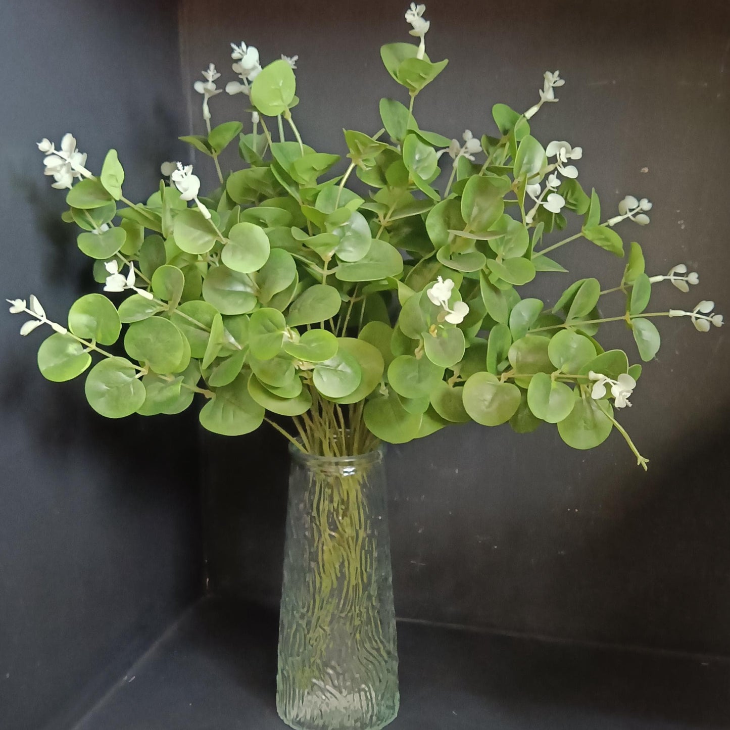 Artificial eucalyptus stems in a textured green glass vase