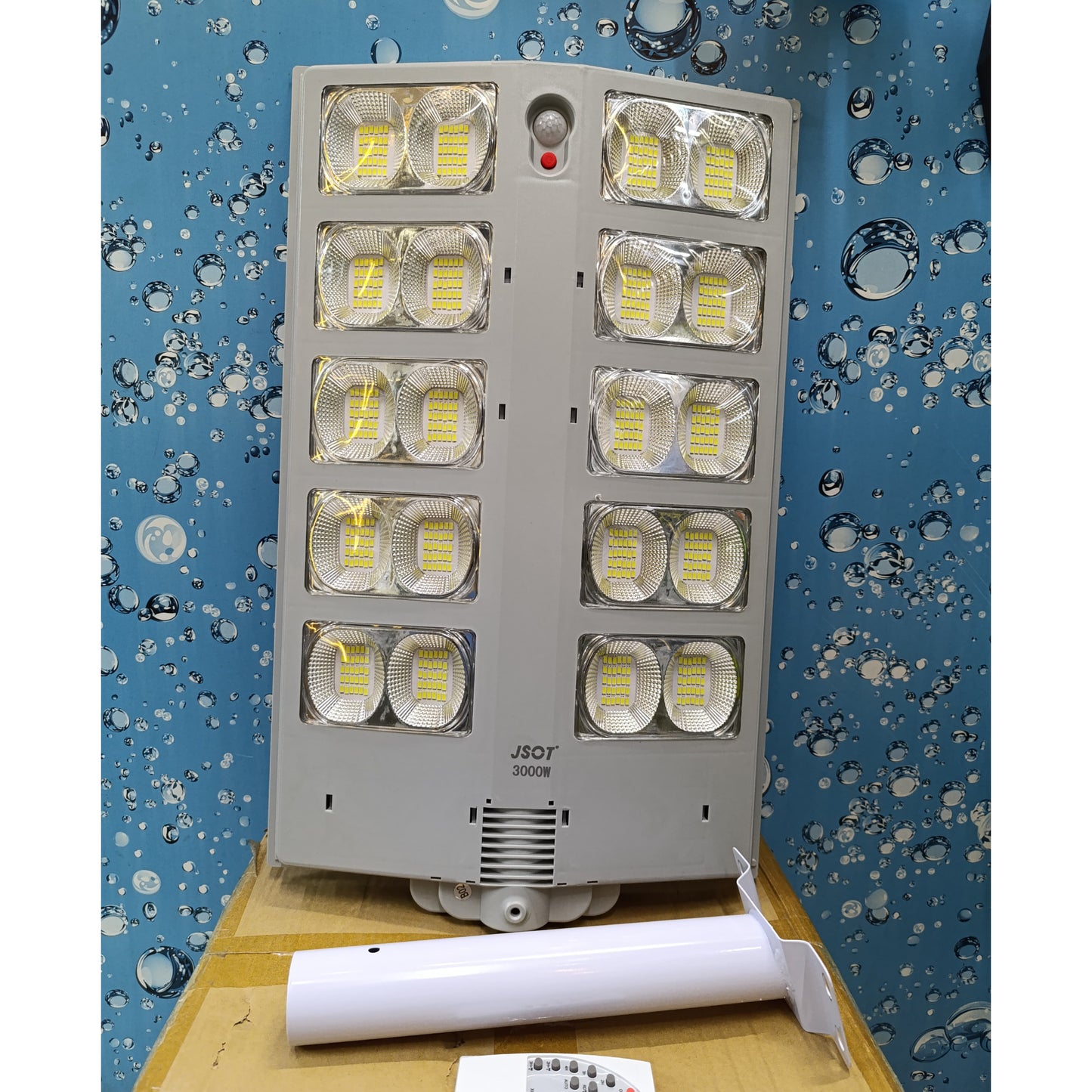 Large grey solar street light with ten LED panels, a mounting pole, and a remote control.