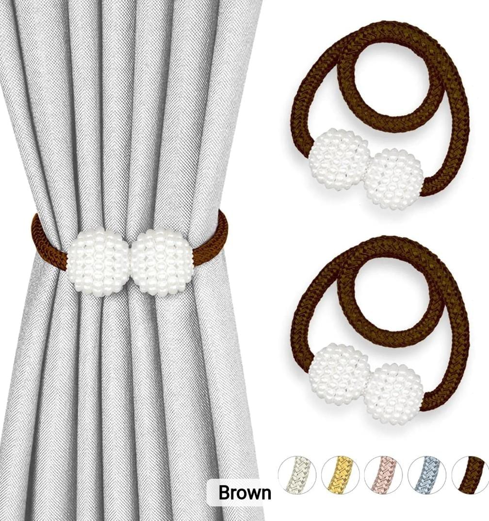 A pair of magnetic curtain holdbacks with thick pearl buckles and hanging balls.