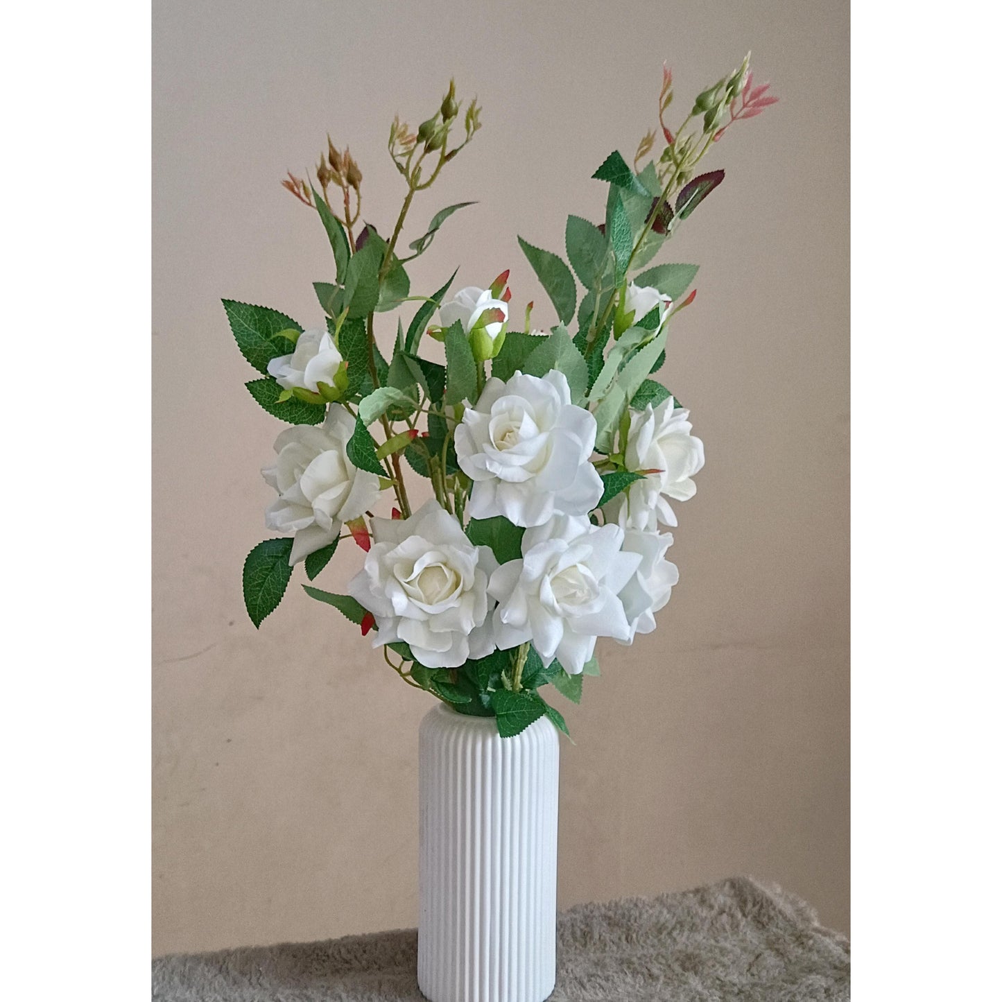 An arrangement of artificial white roses in a white ribbed plastic vase