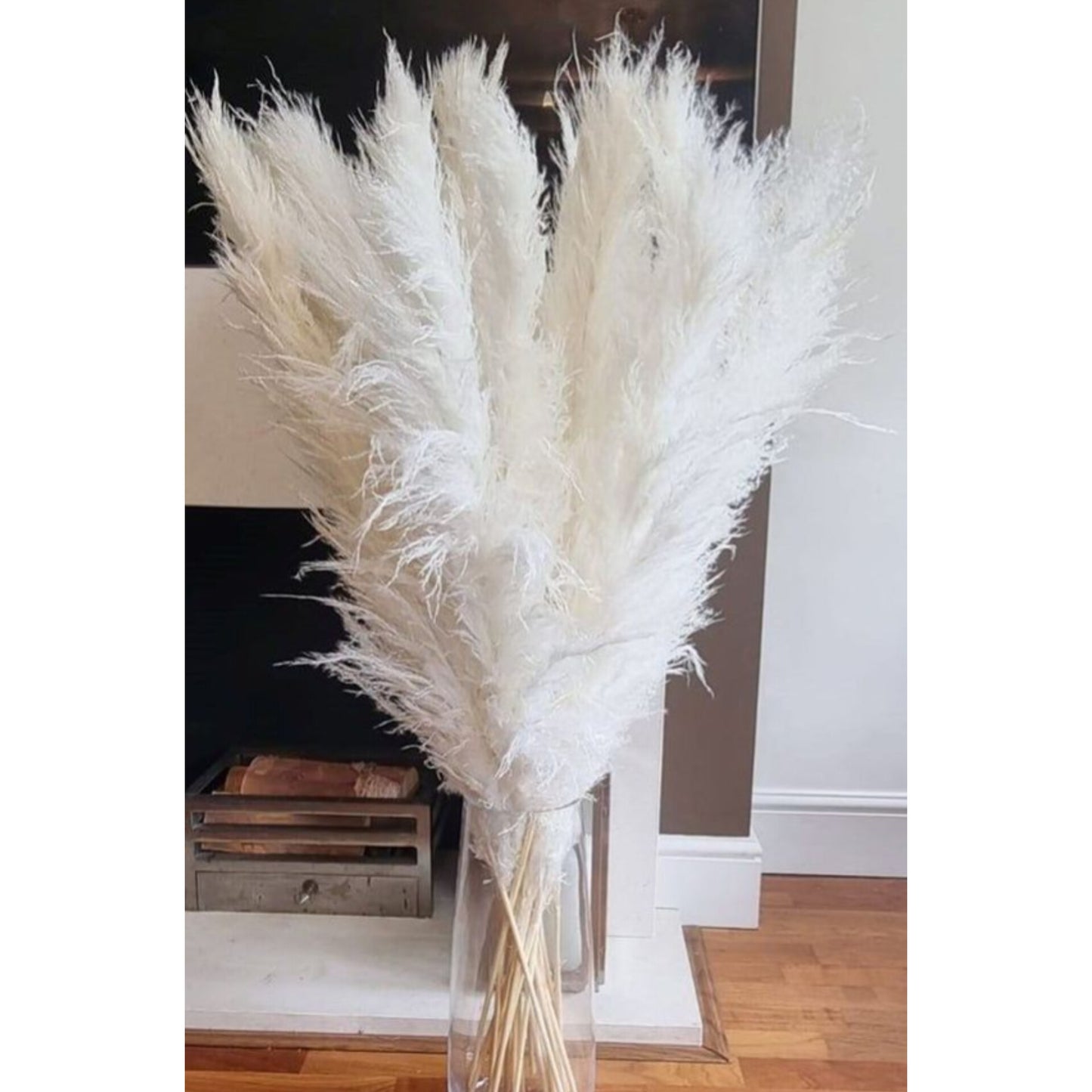 A large bundle of fluffy white dried pampas grass stems arranged in a clear vase.