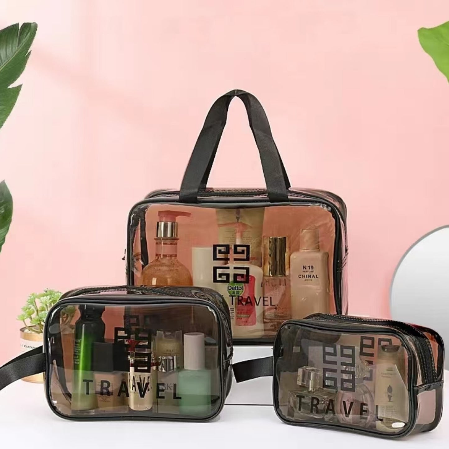Three transparent PVC travel makeup and cosmetic bags with black trim and handles, displaying toiletries inside.