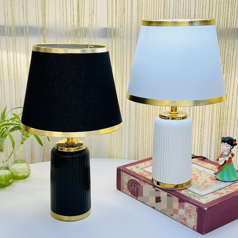 Two vintage table lamps with black and white shades and gold bases.