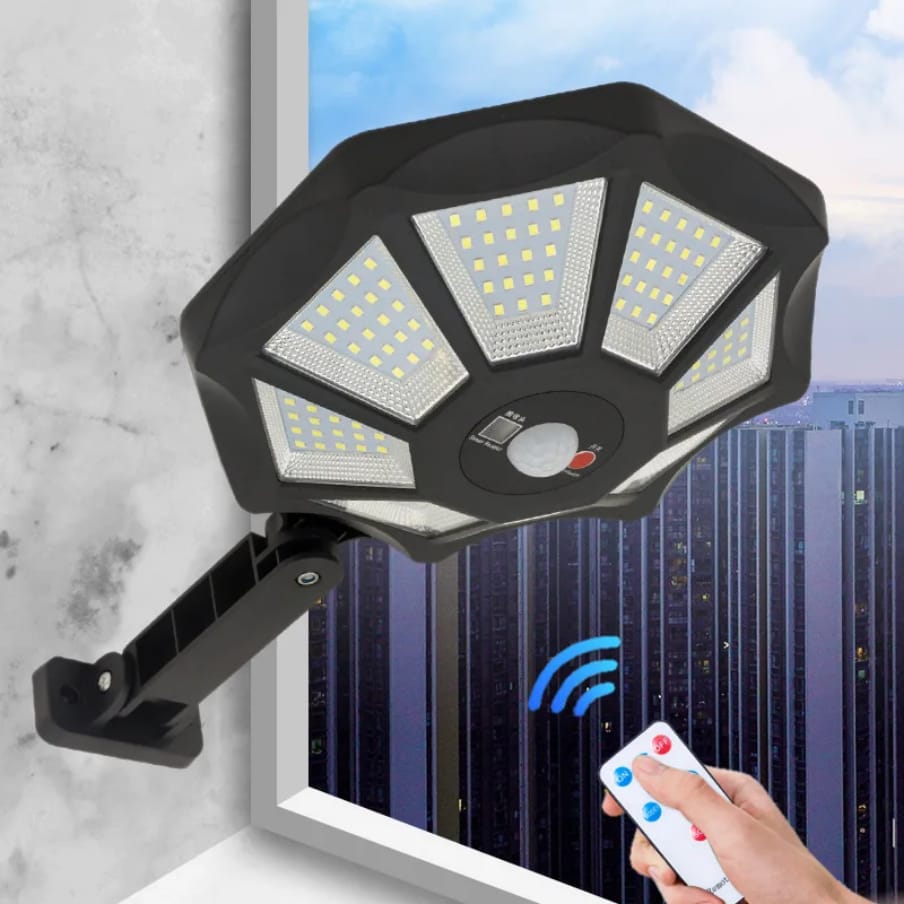 Black hexagonal solar sensor light mounted on a wall with a remote control.