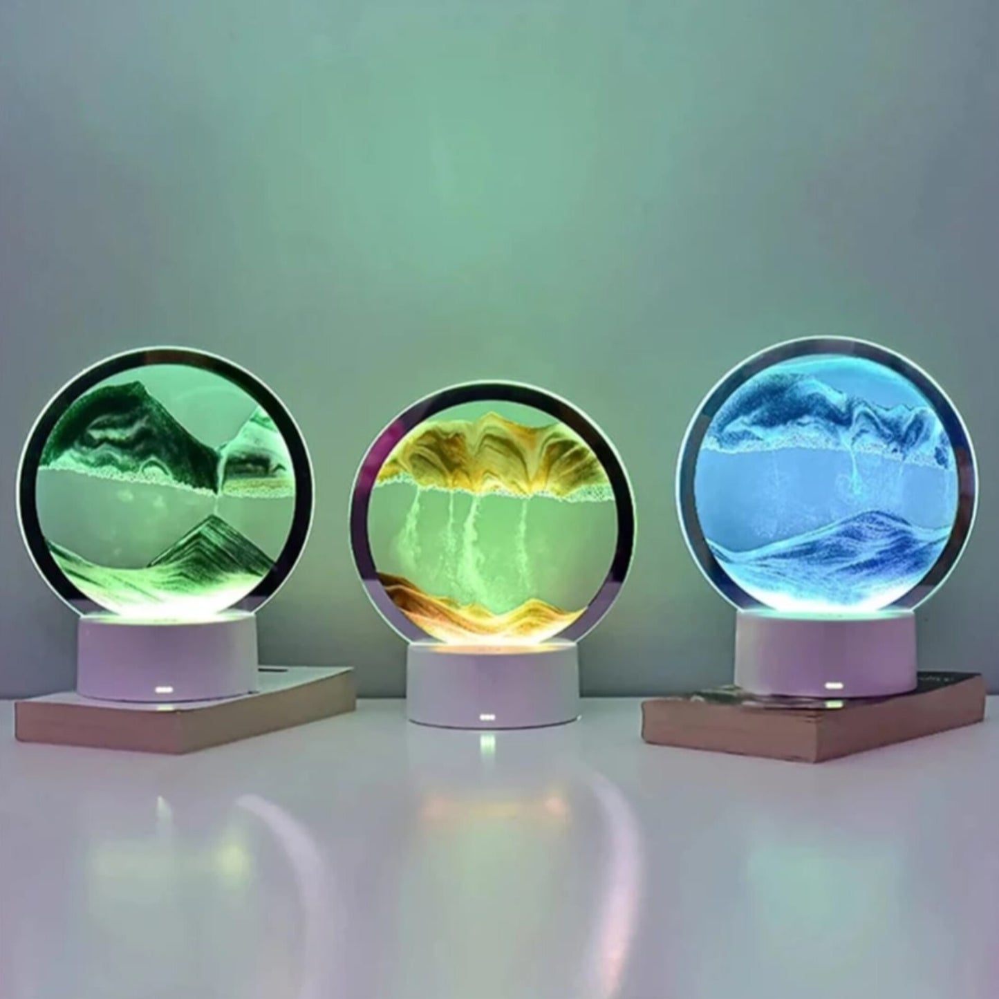Three circular moving sand lamps glowing in green, yellow, and blue light colors.