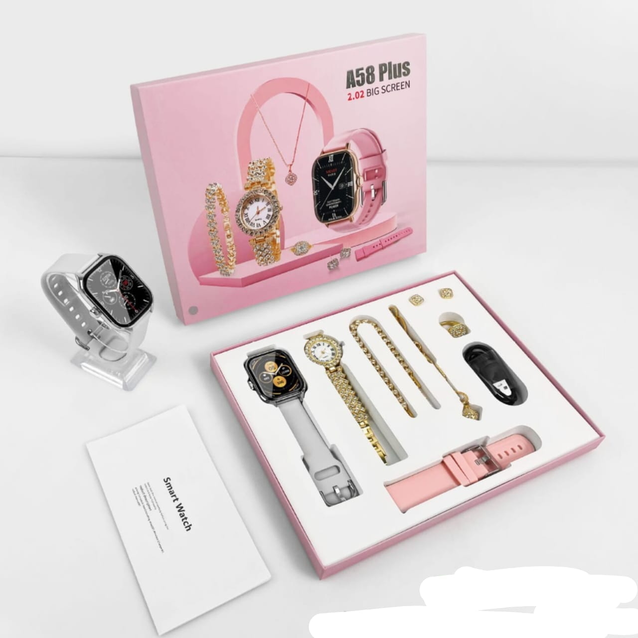 A pink gift box containing a seven piece ladies' accessory set, including a white smartwatch, two interchangeable straps, a gold watch, a necklace, a bracelet, a ring, and a pair of earrings.