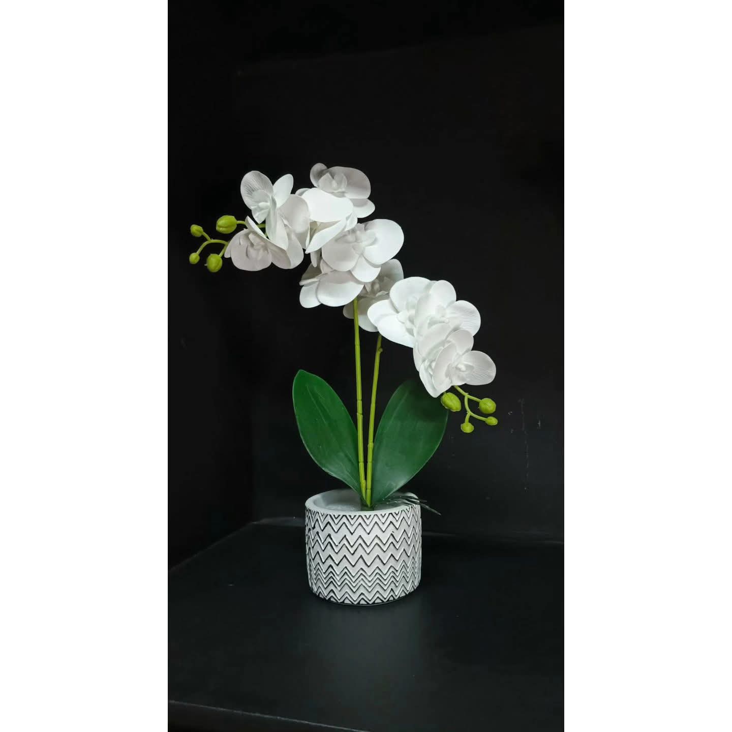 A metallic gold vase with a wavy textured surface holding green stems.