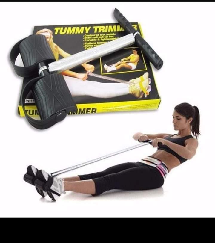 A person using a tummy trimmer gadget, which is designed to assist in ab workouts. The gadget includes a long handle and a wheel-like mechanism for resistance.