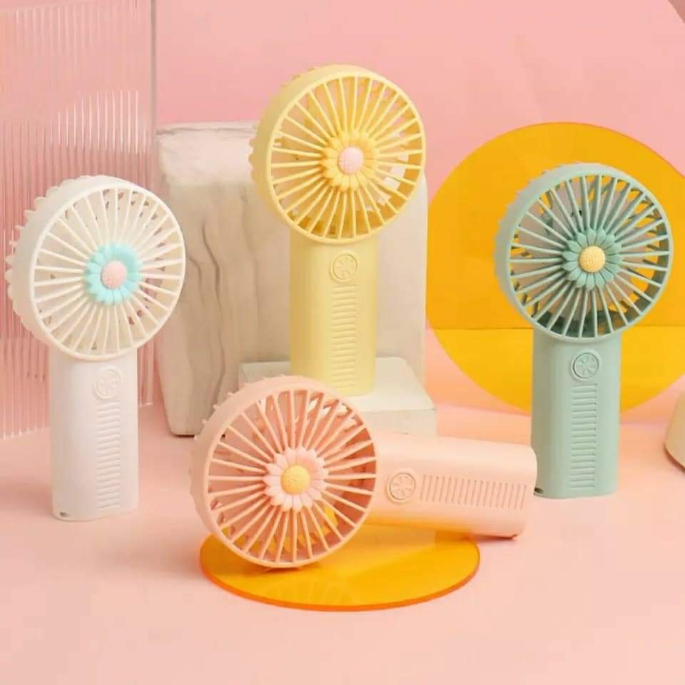 A collection of several handheld, portable, rechargeable mini-fans in colors like pink, blue-green, and yellow, some with a flower design on the grille.
