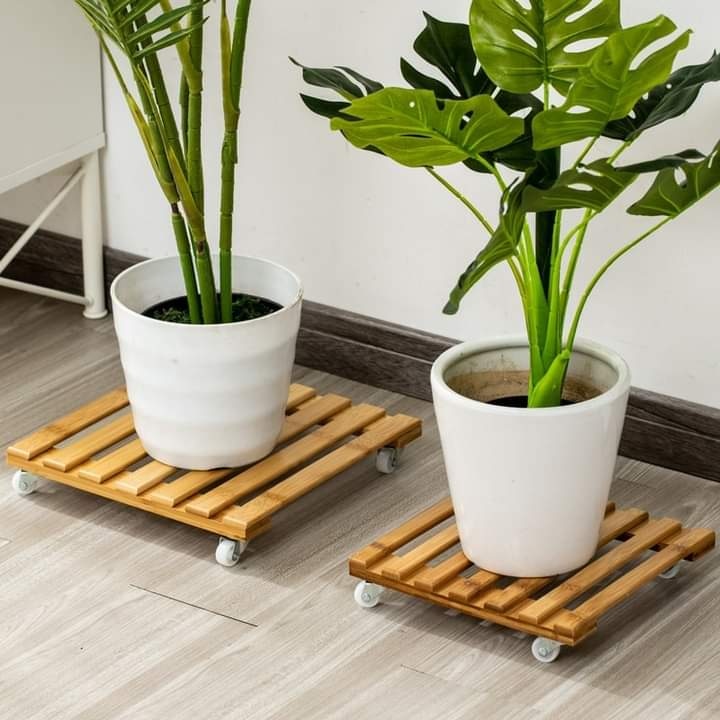 Two square slatted light wood plant stands on white wheels.