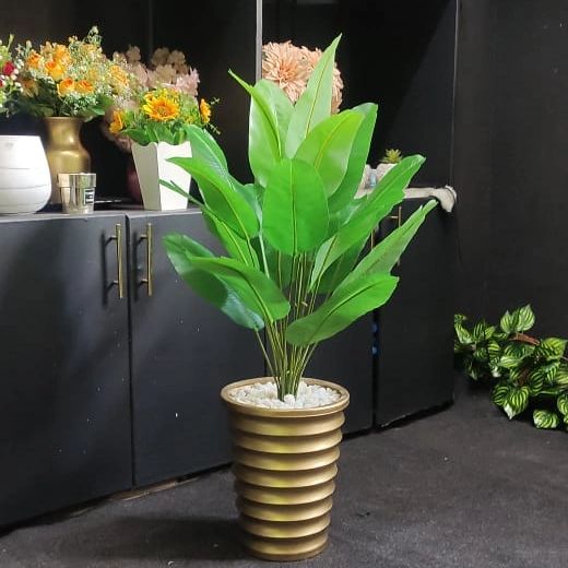 A long trailing green artificial plant cascading from a textured white decorative ceramic vase.