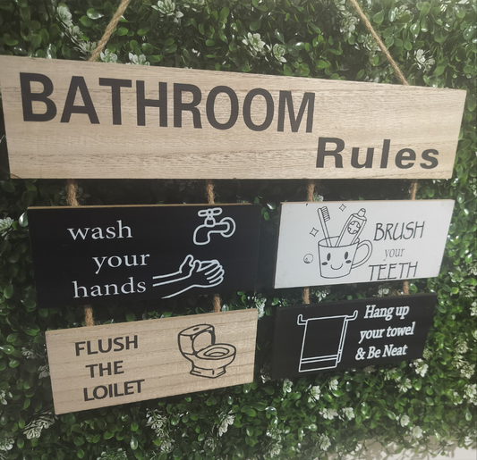A set of wooden wall hangings with humorous bathroom rules written on them, including signs to wash hands, brush teeth, flush toilet, and hang up towel.