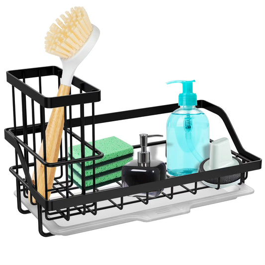 A black stainless steel wire kitchen sink caddy holding a wooden dish brush, green sponge, black soap dispenser, and white scrubbing brush on a kitchen countertop.