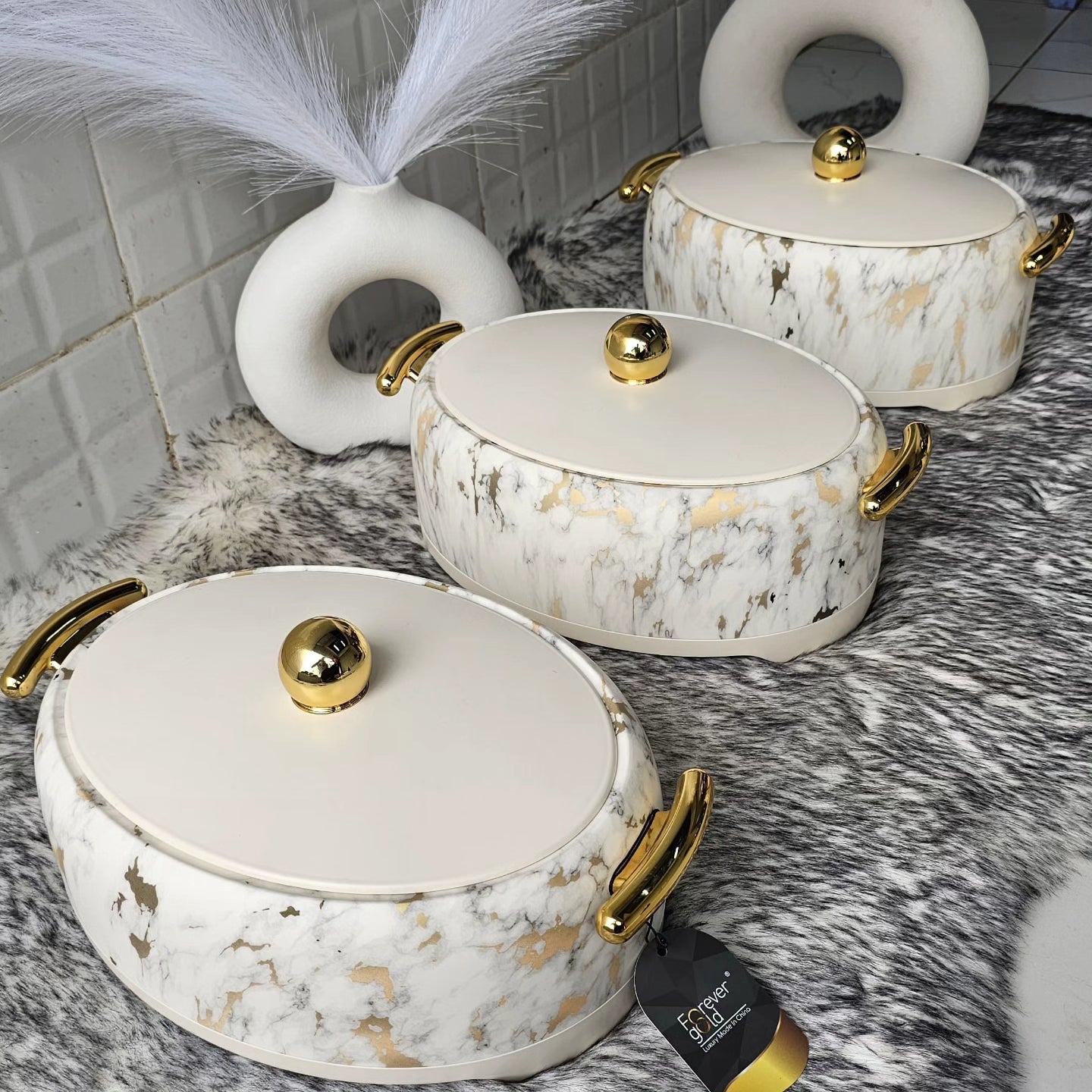 Three insulated hotpots with a marble white finish and gold-colored handles and lids.