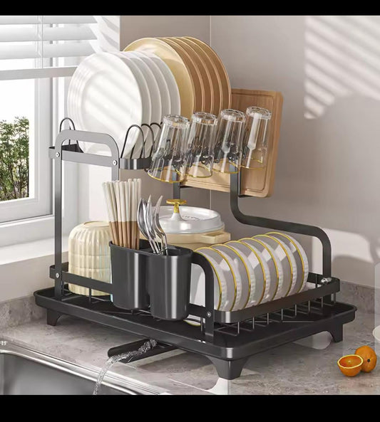 A large, black and silver two tiered metal dish drying rack filled with plates and bowls, showing the attached side holders for cups, utensils, and a cutting board.