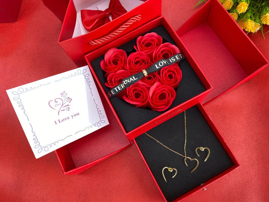 A luxury Valentine's Gift Set featuring a jewelry set (necklace and earrings), a coordinating gift box with preserved red roses, a gift bag, and a heart-themed card.