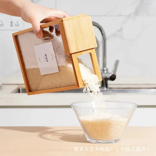 A hand tilting a square bamboo and clear plastic container filled with rice, dispensing the rice neatly into a clear glass bowl in a modern kitchen setting.
