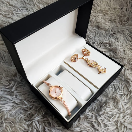 A 4-piece rose gold-toned jewelry set, including crystal stud earrings, a necklace, a ring, and a bracelet, neatly packaged in an orange and white box.