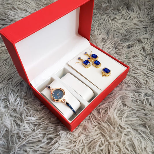 A red and white gift box open to show a gold and blue ladies' watch, a matching blue crystal bracelet, and blue crystal earrings and a ring.