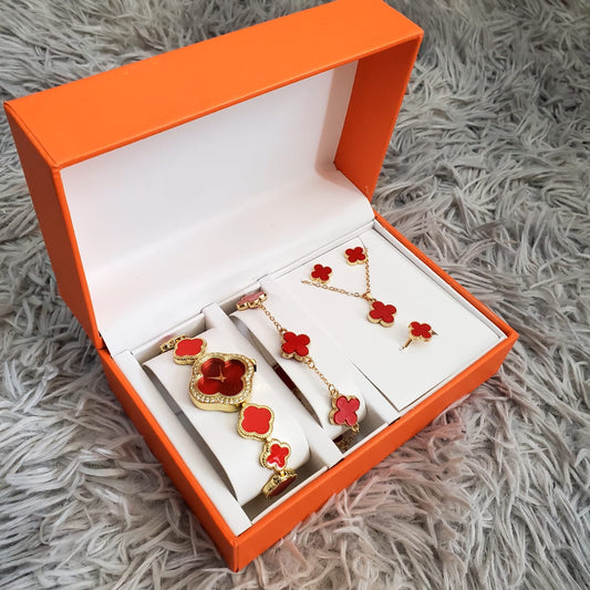 An open orange gift box displaying a rose gold-toned ladies watch with crystals, a matching bracelet, necklace, earrings, and ring, along with a watch adjuster.